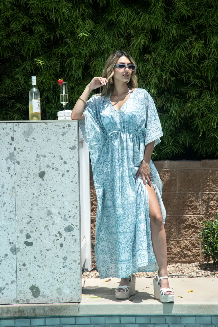 Woman in a light blue kaftan by a pool