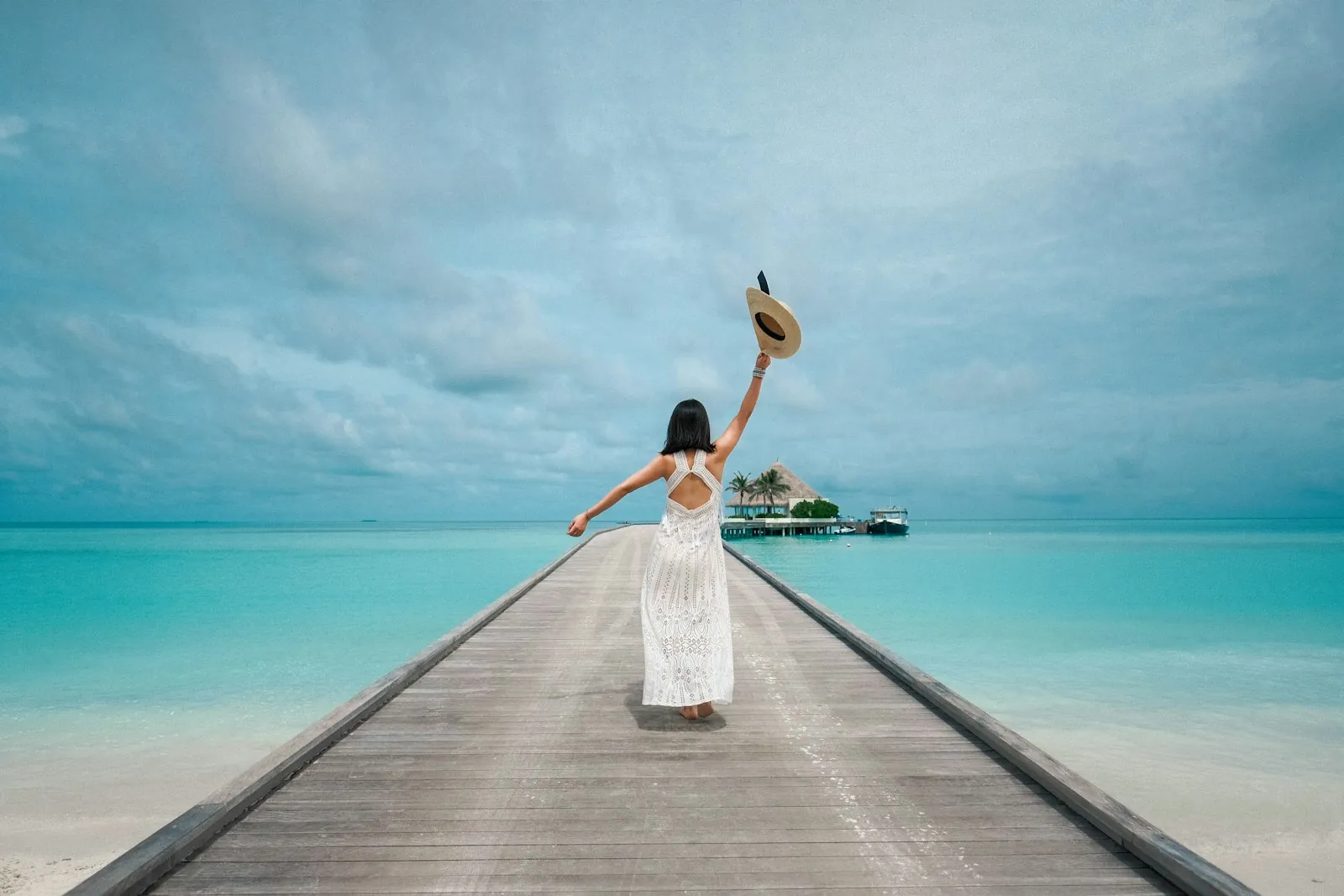 Woman in a white dress on a pier over turquoise water