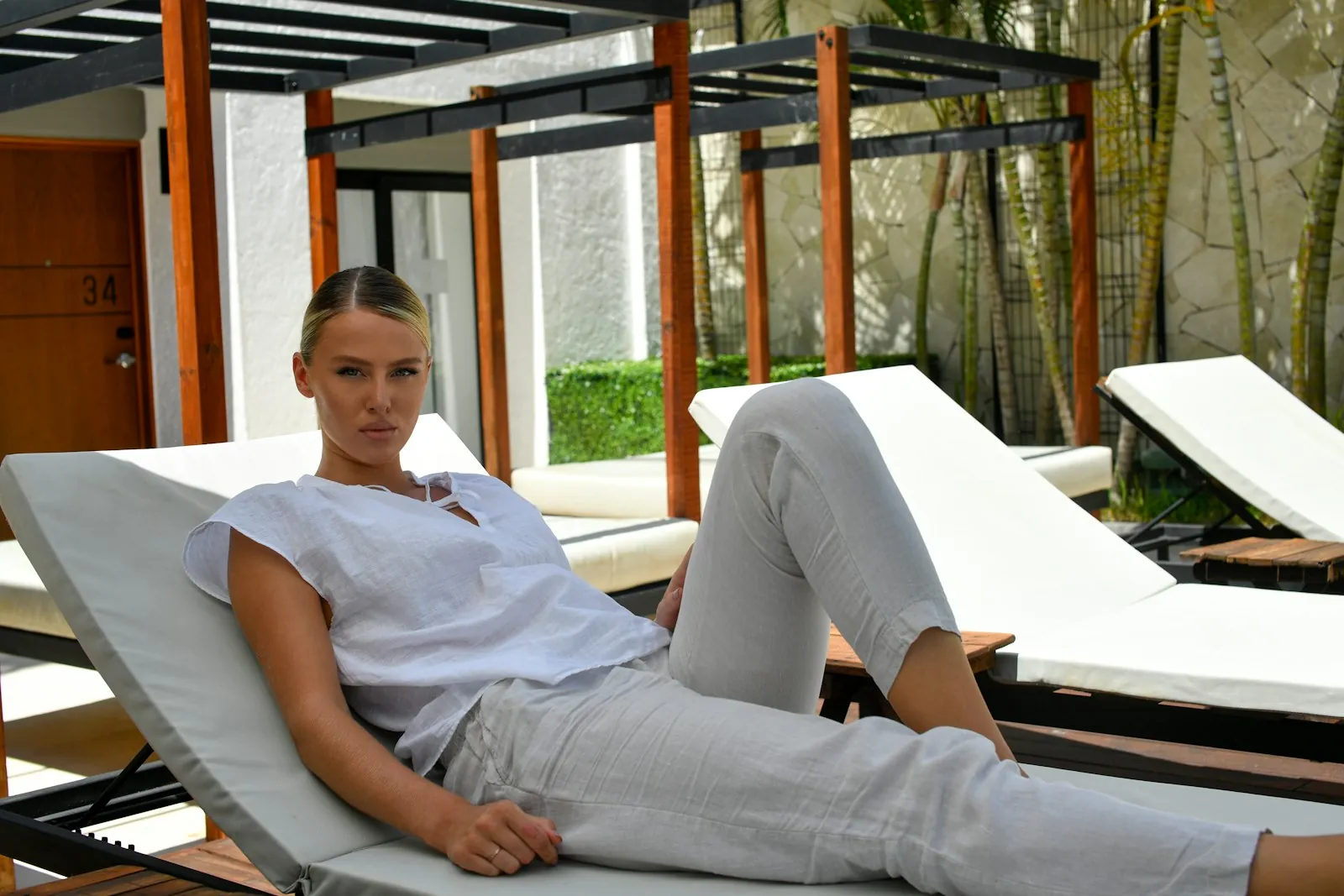 Woman in a white linen top on a poolside lounger