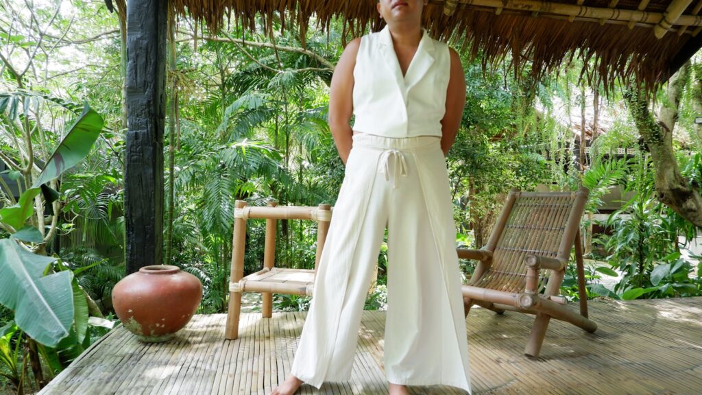 Woman in white outfit standing on a wooden porch.